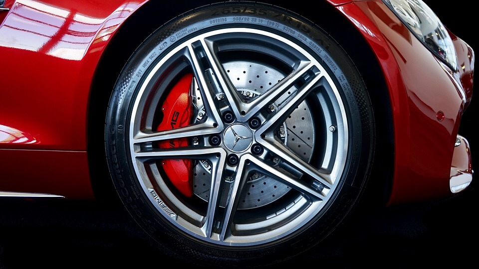 Close-up of high-performance car wheel with disc brakes and red calipers on red sports ca