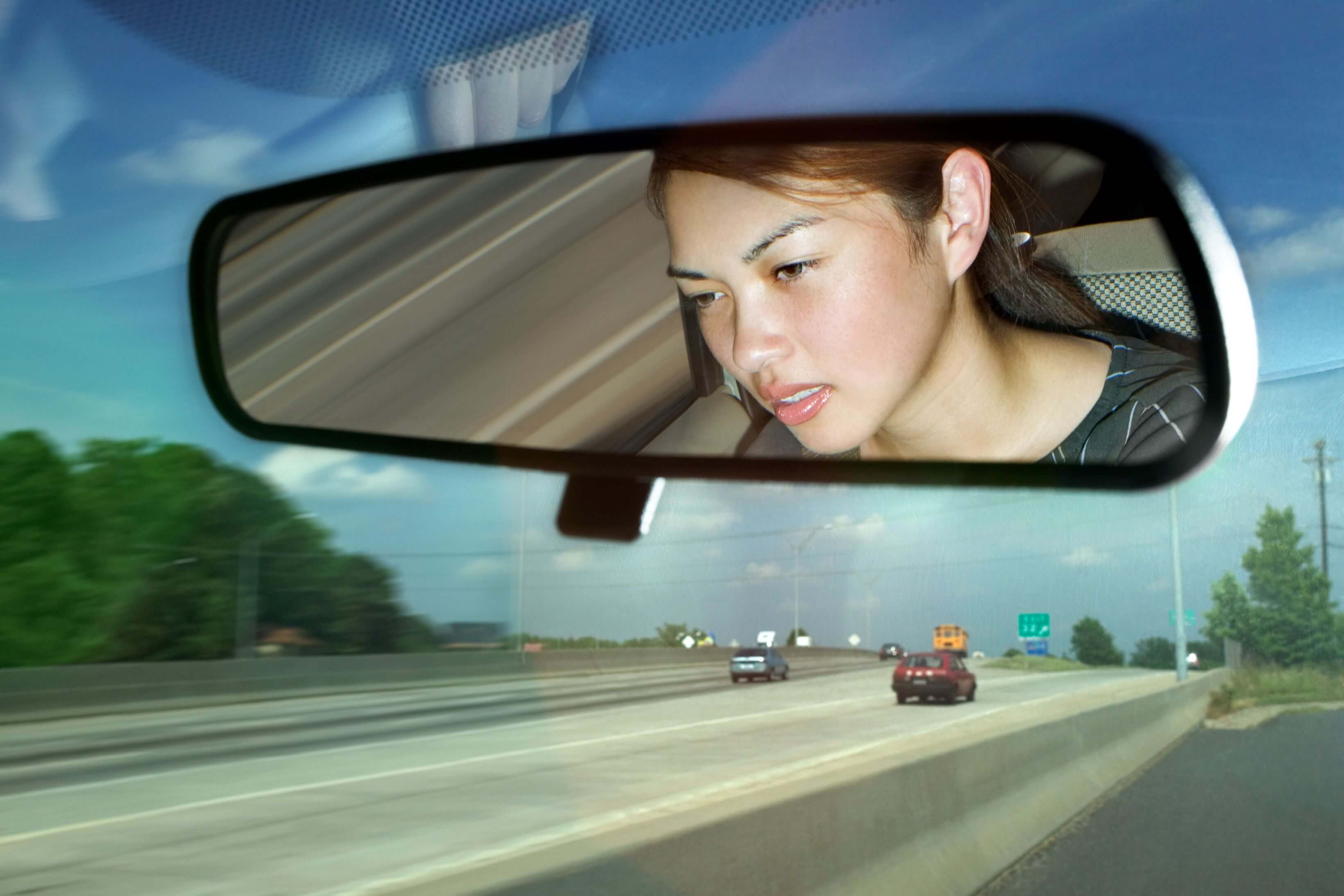 Anxious woman driving, reflected in rearview mirror on highway