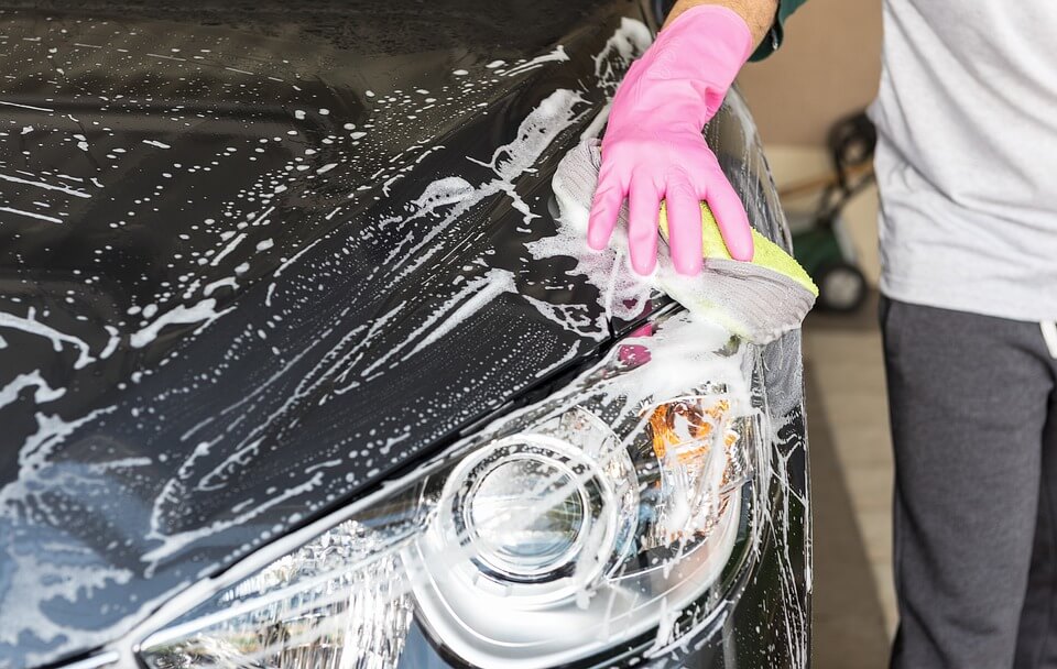 Hand washing a car with soap and sponge for exterior vehicle maintenance and safety awareness